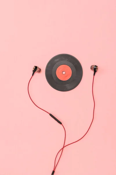 A small red vinyl disc and headphones on a pink background. — Stock Photo, Image