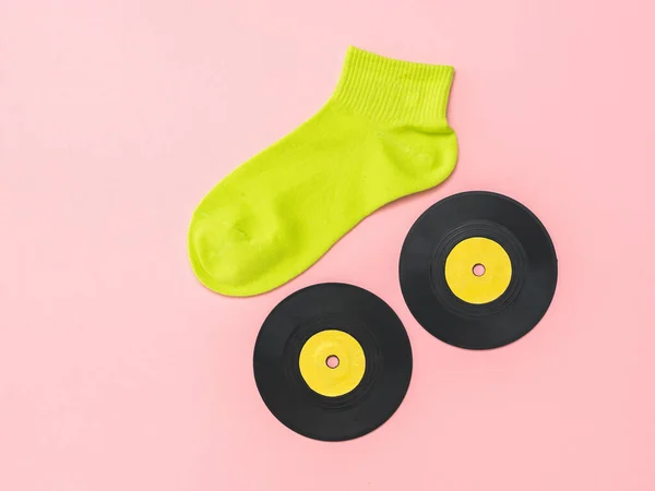 Светло-зеленый спортивный носок и виниловые диски на розовом фоне. Плоский лежал . — стоковое фото