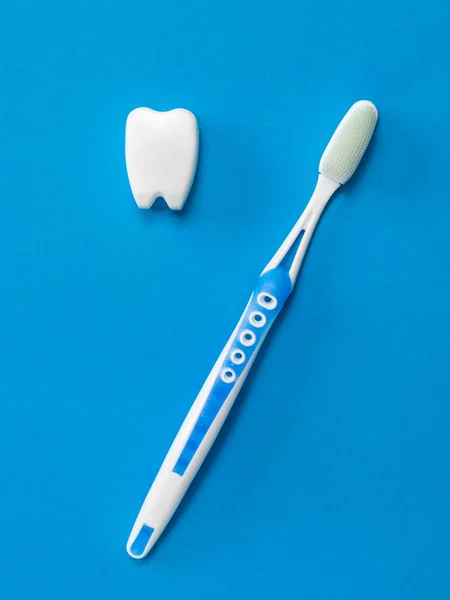 A toothbrush with silicone bristles and a tooth figurine on a blue background. The hygiene and cleanliness of the oral cavity. — Stock Photo, Image