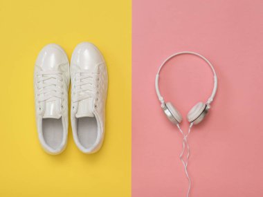 Beyaz kulaklıklar ve pembe ve sarı arka planda beyaz spor ayakkabılar..