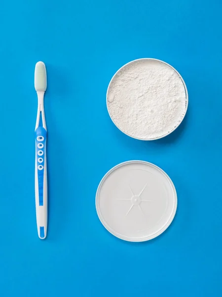 Blue toothbrush and tooth powder on a blue background. — Stock Photo, Image