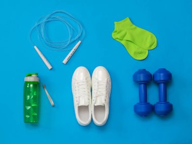 Beyaz spor ayakkabıları ve spor aksesuarları mavi arka planda fitness için.