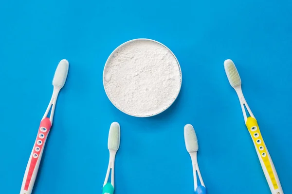 A jar of dental powder and a set of silicone toothbrushes on a blue background. — Stock Photo, Image