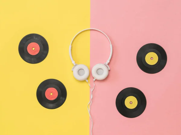 Cuatro discos de vinilo y auriculares blancos sobre fondo rosa y amarillo . —  Fotos de Stock