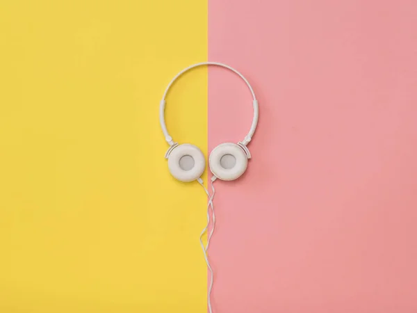 Fones de ouvido brancos com um fio em um fundo amarelo e rosa . — Fotografia de Stock