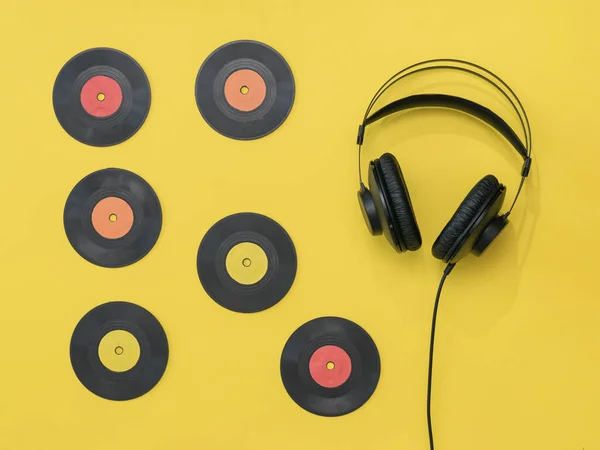 Schallplatten und schwarze Kopfhörer mit Draht auf gelbem Hintergrund. — Stockfoto