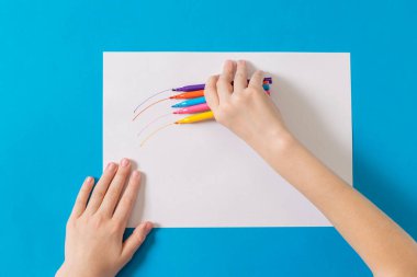 Çocuk beyaz bir kağıda beş işaret çiziyor..