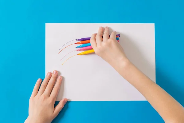 L'enfant dessine avec cinq marqueurs sur une feuille blanche de papier . — Photo