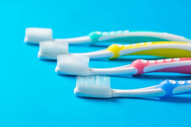 Mavi arka planda silikon kılları olan çok renkli diş fırçaları. Ailede ağız temizliği kavramı.