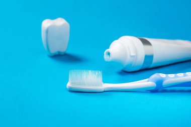 Bir diş biblosu, bir tüp diş macunu ve mavi arka planda silikon kılları olan mavi bir diş fırçası..