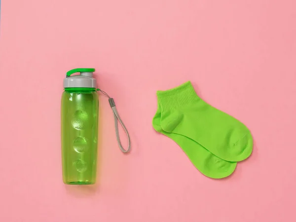 Зеленые спортивные носки и зеленая бутылка воды на красном фоне. Плоский лежал . — стоковое фото