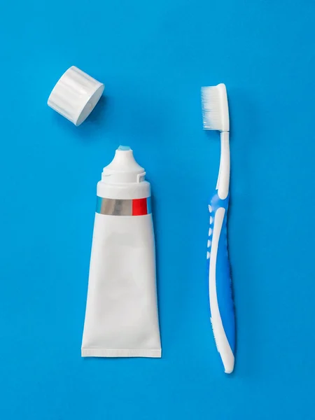 A toothbrush and an open tube of toothpaste on a blue background. Flat lay. — Stock Photo, Image