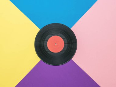Çok renkli soyut bir arkaplanda büyük bir vinil disk. Vinil disk kolajı. Düz yatıyordu.