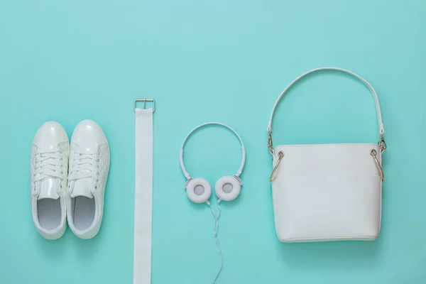 Sapatilhas brancas, fones de ouvido brancos, cinto branco e saco branco em um fundo leve. Depósito plano . — Fotografia de Stock