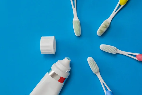 An open tube of gel toothpaste and toothbrushes on a blue background. Flat lay. — Stock Photo, Image