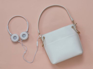 Pastel arka planda beyaz kulaklıklı beyaz bir kadın çantası. Düz yatıyordu.