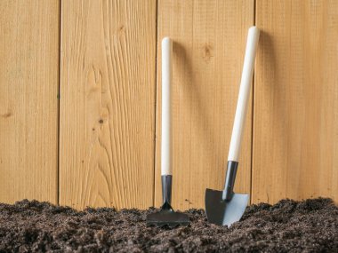 Tahta bir çitin yanında kürek ve tırmık..