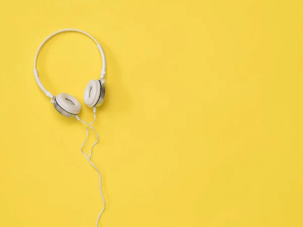 Білі навушники з дротом на яскраво-жовтому фоні . — стокове фото