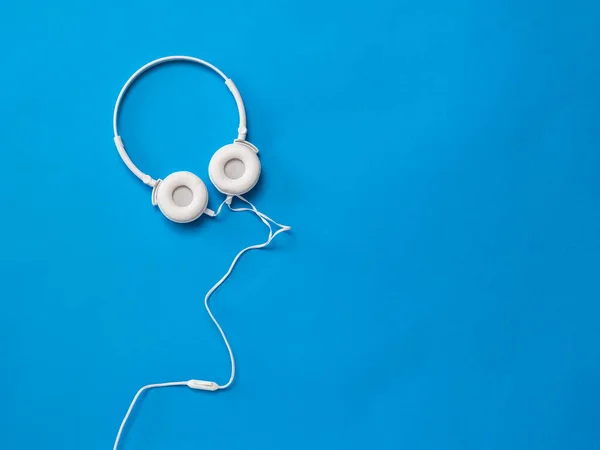 Білі навушники з дротом на насиченому синьому фоні . — стокове фото