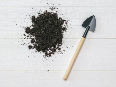 Tahta saplı bir kürek ve ahşap arka planda verimli toprak..