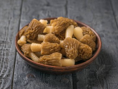 Ahşap bir masa üzerinde taze morellerle dolu bir kil tabaka..