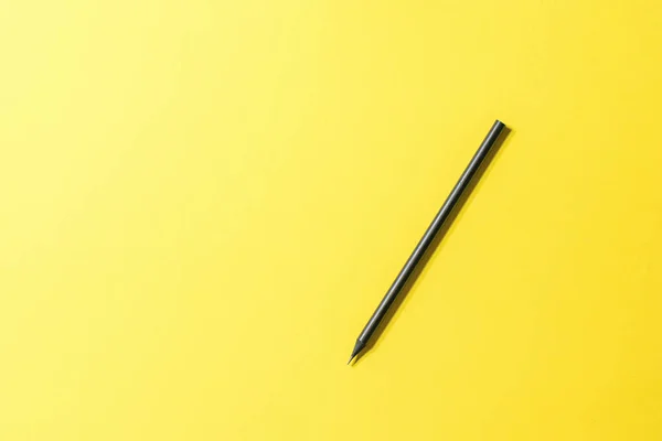 Schwarzer Graphitstift auf leuchtend gelbem Hintergrund. — Stockfoto