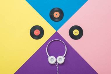 Soyut bir arkaplanda kablo ve vinil diskleri olan beyaz kulaklıklar..