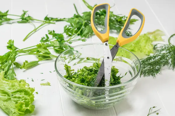 Tesoura de salada em uma tigela de vidro com ervas picadas . — Fotografia de Stock