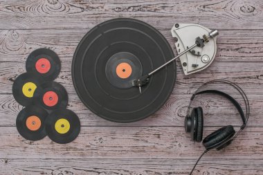 Vinil diskler, kulaklıklar ve tahta arka planda bir oyuncu..