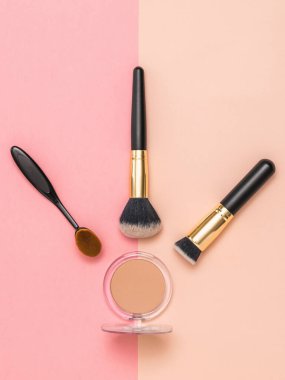 İki renkli arkaplanda makyaj fırçası ve toz..
