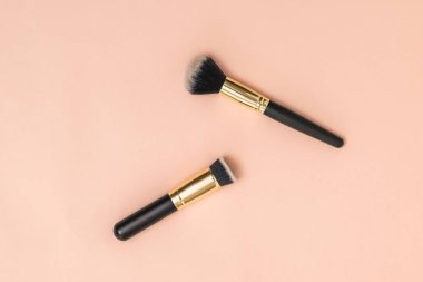 Pastel arka planda yüz bakımı için iki fırça.