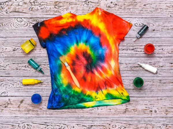 T-shirt pintada no estilo de tintura gravata com cores em um fundo de madeira. Depósito plano . — Fotografia de Stock