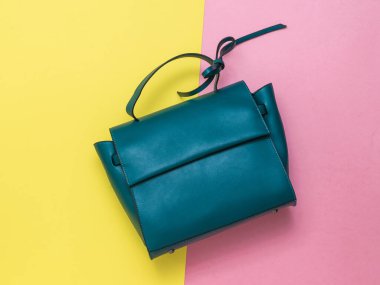 Sarı ve kırmızı arka planda koyu yeşil kadın çantası. Yukarıdan görünüşü.