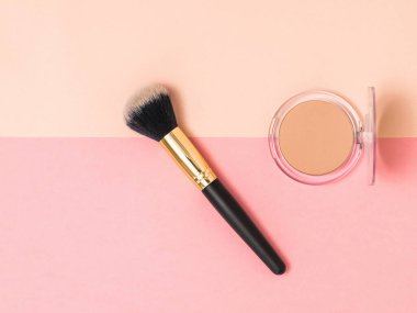 Açık bir barut kavanozu ve iki renkli arka planda makyaj fırçası..