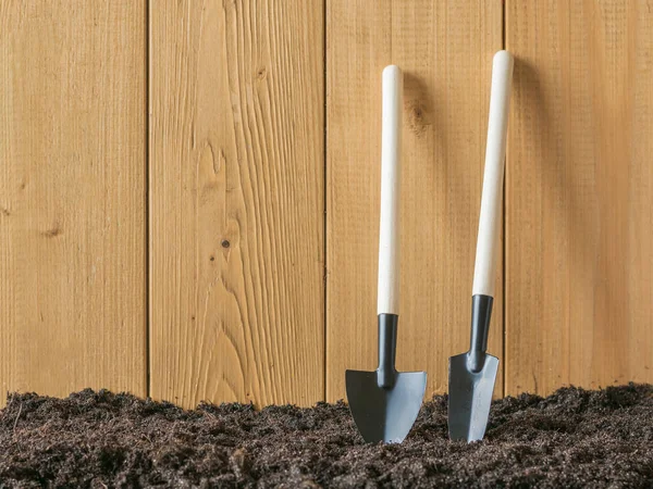 Palas para cavar y quitar malezas cerca de una valla de madera . — Foto de Stock
