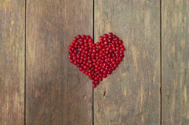 Kırmızı boncuk ağaç tohum kalp kahverengi ahşap üzerine