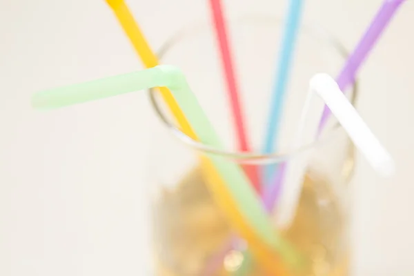 Multicolored tubes in a glass with a yellow drink — Stock Photo, Image