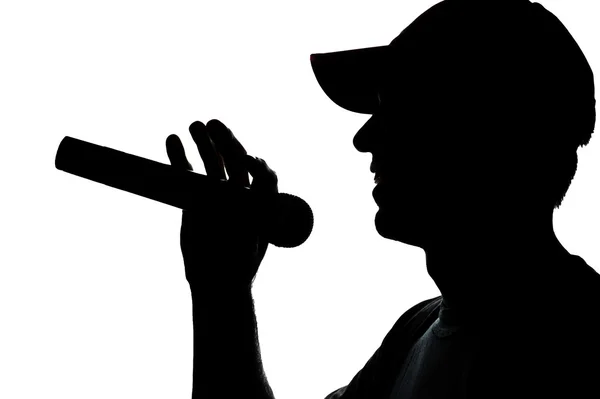 Νεαρός άνδρας στο καπάκι τραγουδώντας σε ένα μικρόφωνο — Φωτογραφία Αρχείου