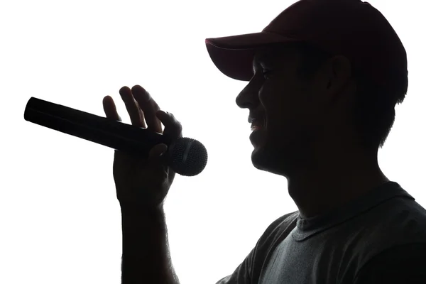 Young man in cap singing into a microphone — Stock Photo, Image