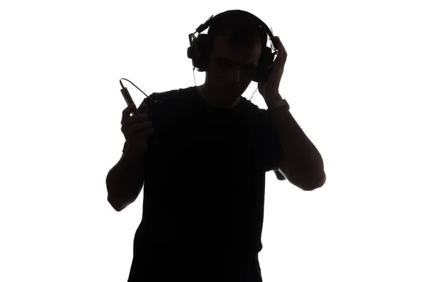 Silhueta de um jovem com um smartphone com fones de ouvido — Fotografia de Stock