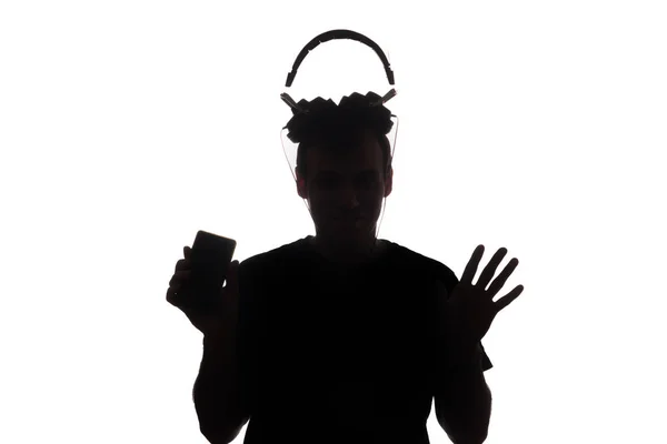 Σιλουέτα ενός νεαρού άνδρα με ένα smartphone με τα ακουστικά — Φωτογραφία Αρχείου