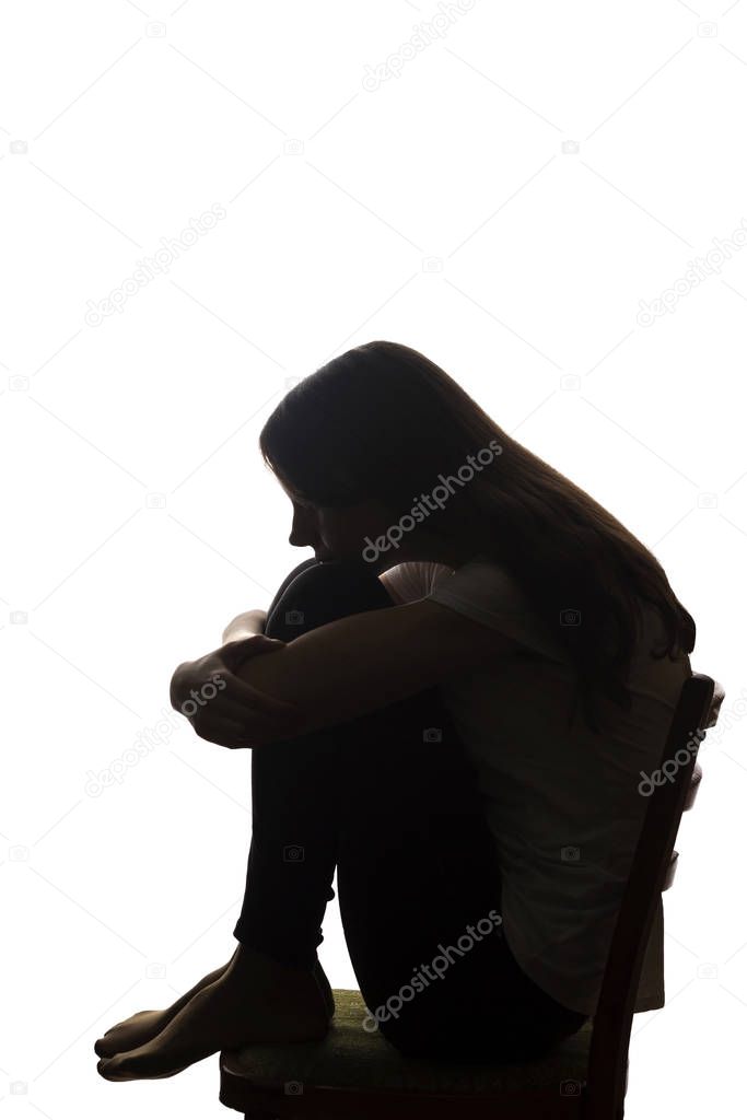 Young beautiful girl in grief hugged her knees - silhouette