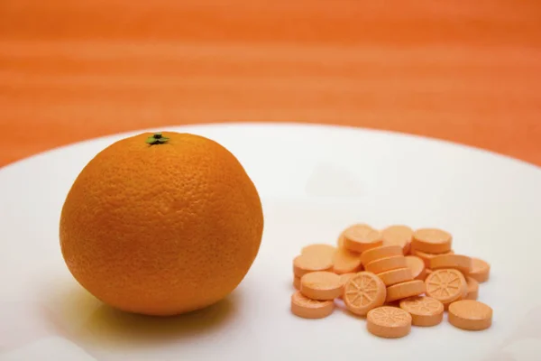 Tablets and orange on a white background - vitamin, protection against influenza during quarantine, coronavirus, covid19