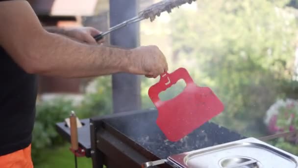 Man blows coals in brazier, swinging a red plastic cutting board. — ストック動画