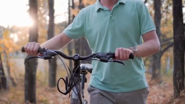 Hombre en gafas va con la bicicleta en el bosque y sonríe — Vídeos de Stock