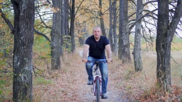 Чоловік катається на велосипеді в осінньому лісі — стокове відео