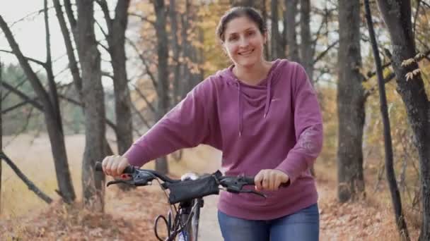 Frau läuft mit Fahrrad im Wald — Stockvideo