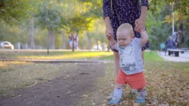 İlk adım çocuk yapar, annesi ona yardım et. Sonbahar park.