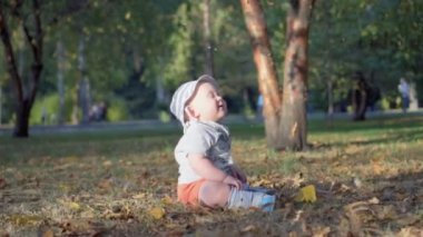 Bebek ormanın içinde. Düşen sonbahar yaprakları. Ağır çekim 100 fps.