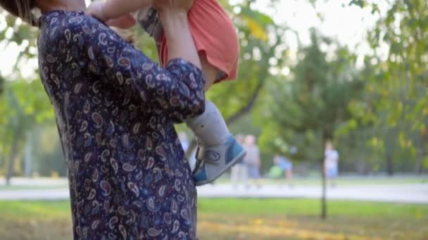 Mother throwing up her baby boy. They are laughing. Slow motion in the park. — Stockvideo